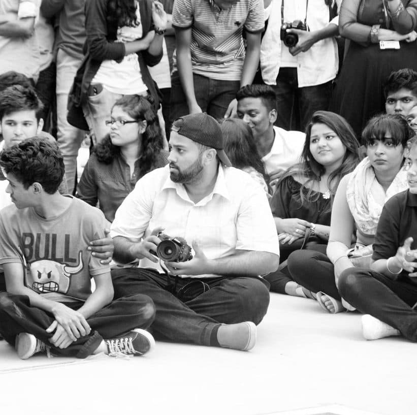 Harsh V Singh on assignment, seated with a camera among a press pack